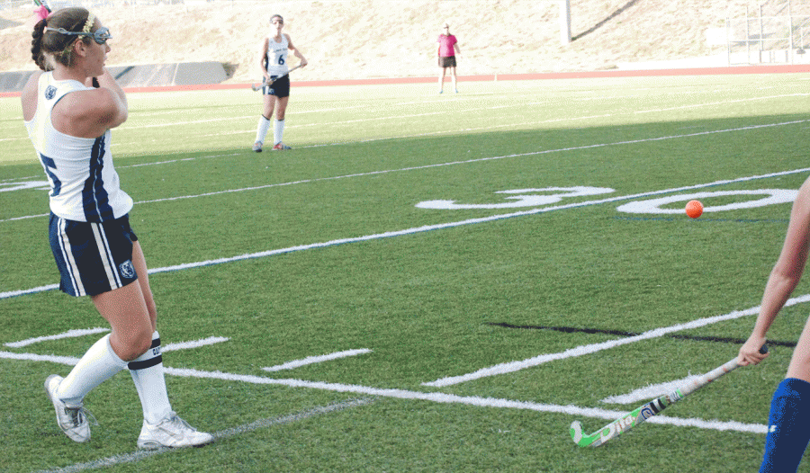Field Hockey member hits a ball at a game against Cherry Creek 