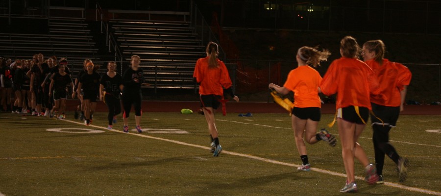 Senior and underclassmen Powder Puff players run toward each other to high five post-game.