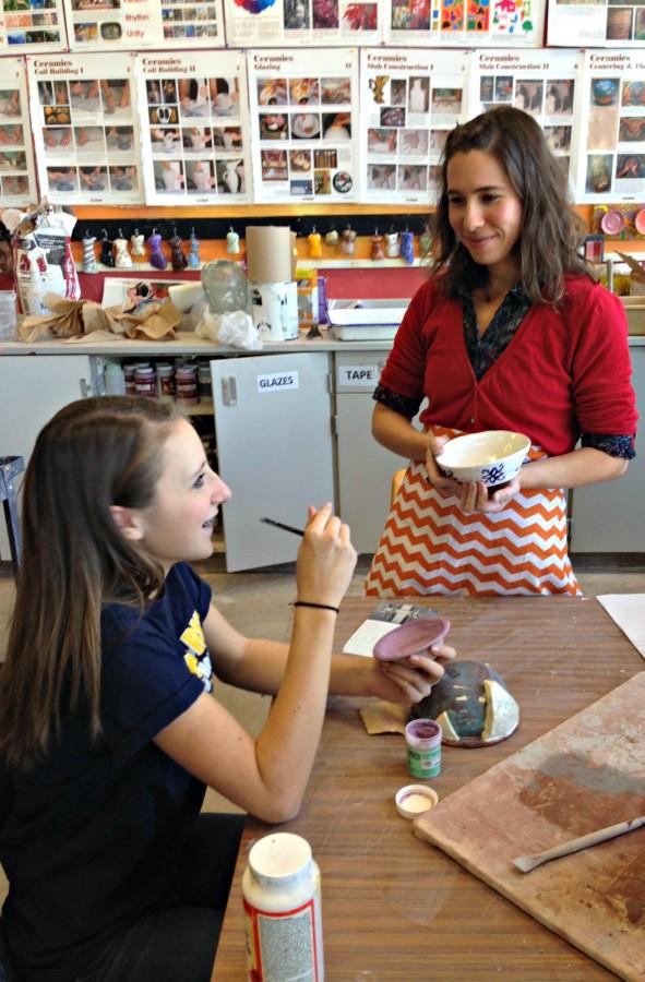 Ms. Crow instructing a student on how to properly paint a bowl.