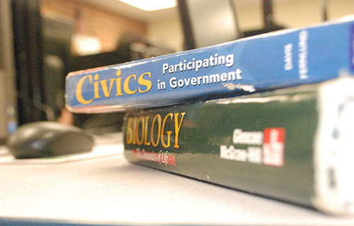 A typical student’s load of already outdated textbooks stacks her work space.