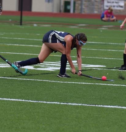 Amy Cooper diving for the ball in a field hockey game