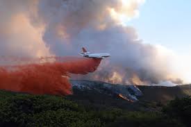 A plane drops fire retardant to slow the progress of a fire. 