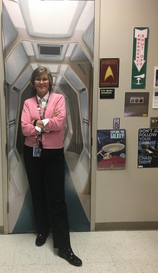 Mrs. Gregory poses in front of her spaceship themed door cover in her classroom. “My main interest, just by looking around the room, is Astronomy,” said Mrs. Gregory.