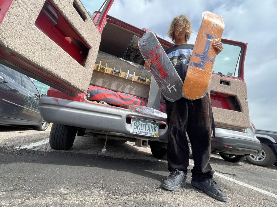Noah Epstein posing in front of the Skate Tank holding some new boards. He uses his van as a mobile skate shop where he sells boards and gear out the back.
