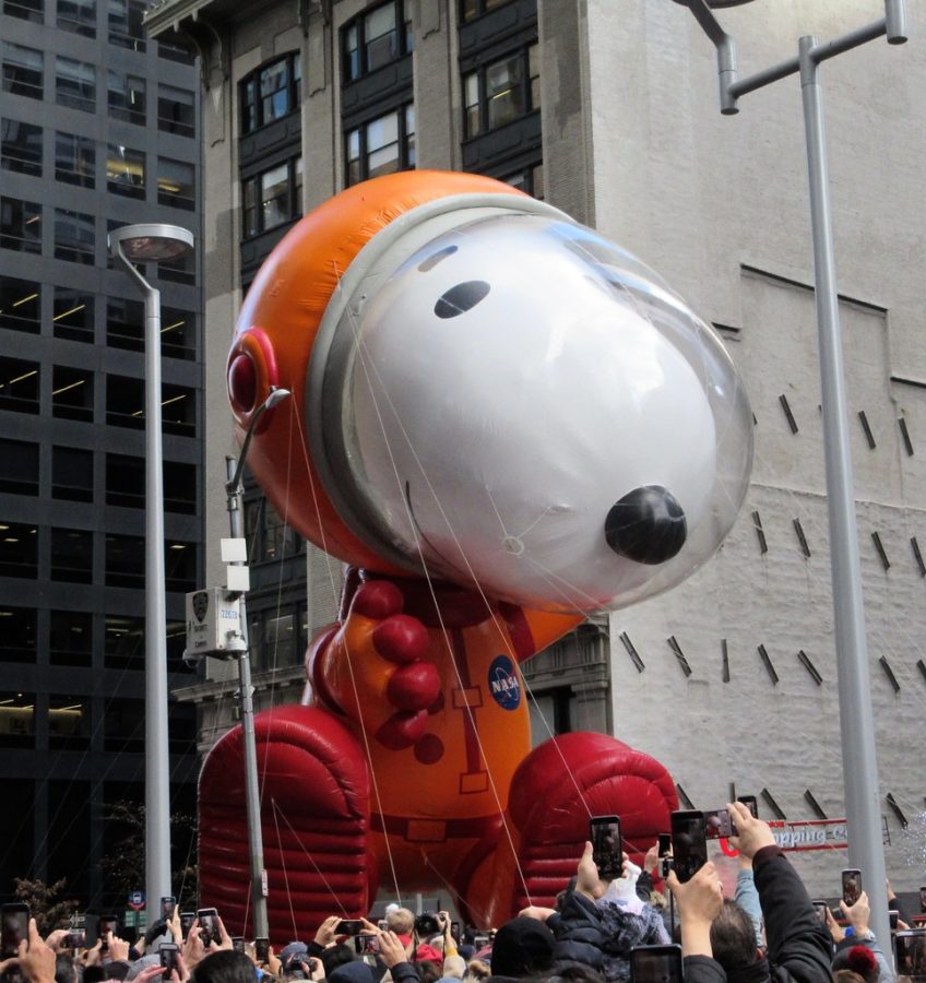 Astronaut Snoopy, designed by Joey Ammons, flies above the crowd as spectators photograph and record the beloved beagle character. 
